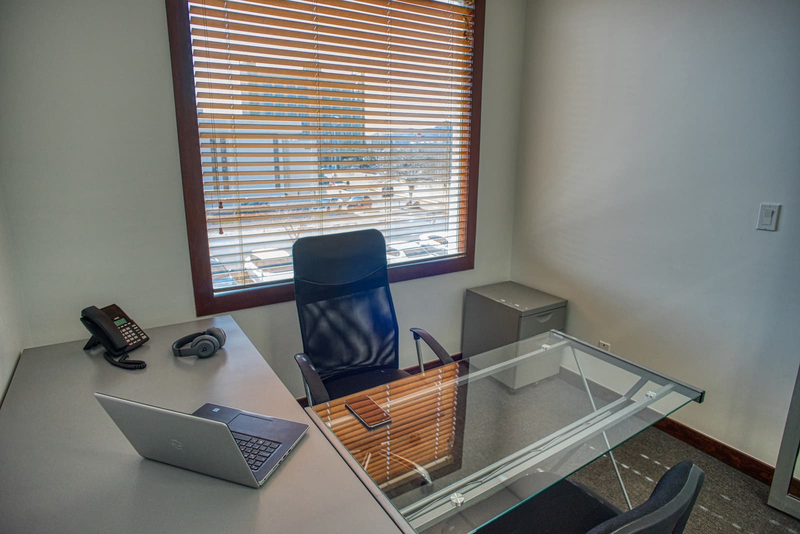 Oficina privada amueblada con escritorio de cristal y ventana en un centro de negocios BCM
